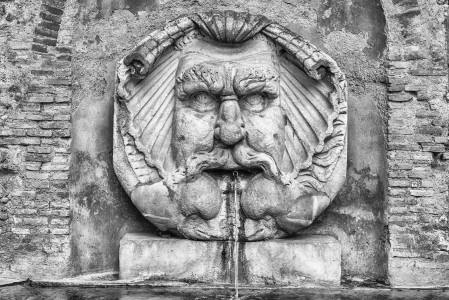 Fountain with large mask in the courtyard of Santa Sabina Basilica in Rome , Italy