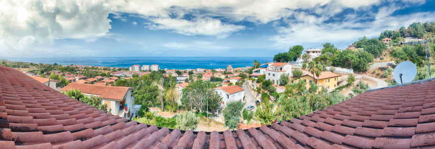 Panoramic aerial view over roof tiles and the coastline in Calabria on the thyrrenian sea, Italy