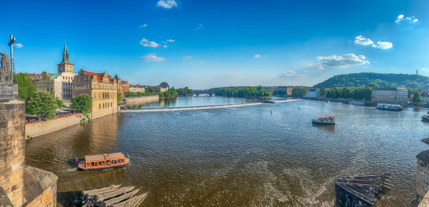 Panoramic view of Vltava River with tour boats and historic architecture in Prague, Czech Republic