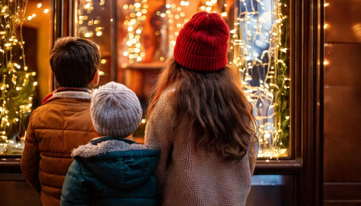 Children admiring a magical Christmas window display on a snowy evening. AI-generated content